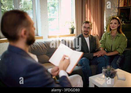 Family psychologist taking notes while listening to couple during therapy Stock Photo