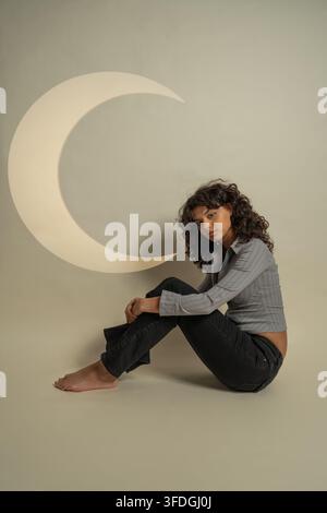 Young woman sitting on the floor with a crescent moon symbol Stock Photo