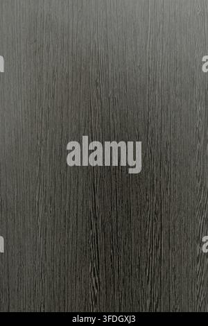 Abstract dark grey and black wooden grain background with vertical line pattern, close up of smooth laminate timber veneer texture. Stock Photo