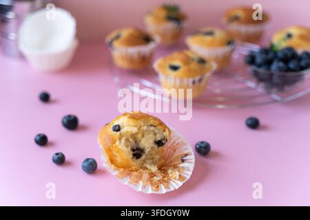 Close-up of a homemade blueberry muffin with fresh blueberries arranged on a pastel pink background Stock Photo