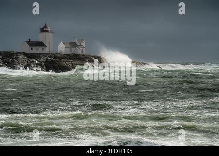 Beacon resistance to wave impact is shown as surf explodes against rocks beside Langoytangen lighthouse in Norway, supporting maritime safety, navigat Stock Photo
