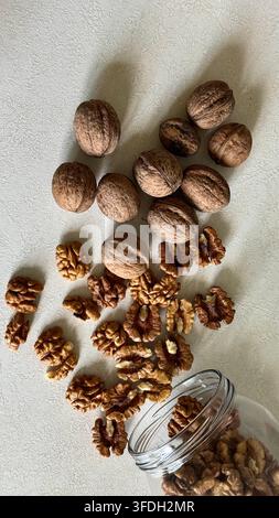 Whole walnuts and walnut kernels arranged as if spilling from a jar, creating a natural autumn food composition with copy space. Stock Photo