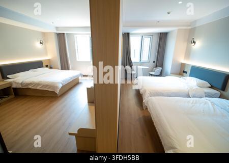 Modern hotel suite divided into two bedroom areas with clean beds and warm lighting. Stock Photo