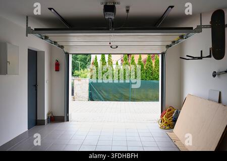 Open sectional garage door with automatic opener inside residential garage. Home parking and practical garage organization Stock Photo