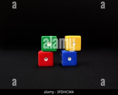 Colored dice  scattered on a uniform dark black background. Stock Photo