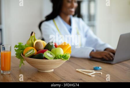 Nutritionist working on laptop, giving online consultation to client at clinic Stock Photo