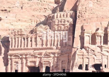 Visitors marvel at the stunning rock-cut architecture in Petra, Jordan under clear skies. The ancient city showcases impressive carvings from centurie Stock Photo