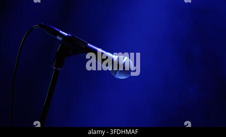 Microphone on stand under blue stage lighting with bokeh background Stock Photo