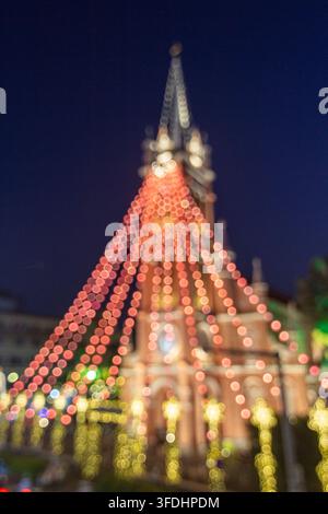 Colorful red and yellow decorative lights form circular bokeh around blurred urban architecture beneath a dark blue night sky. Stock Photo