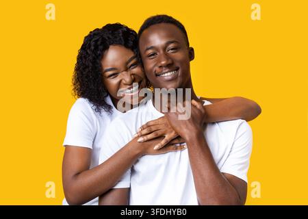 Portrait of african man and woman hugging on yellow Stock Photo