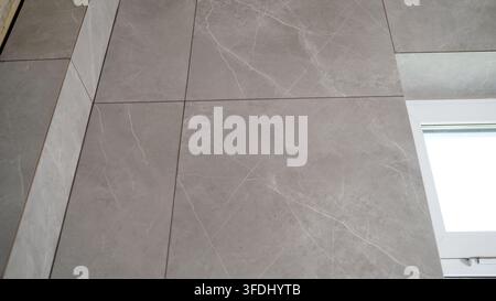 Gray marble effect tiles on wall and floor with white window frame Stock Photo