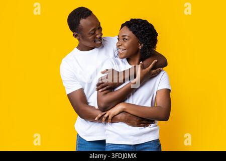 Happy black man and woman embracing, looking at each other Stock Photo
