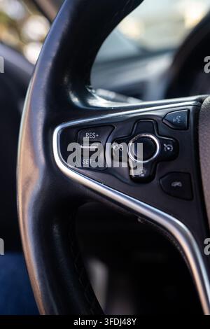 Car steering wheel buttons control media and cruise functions close up. Multifunction controls emphasize driving comfort and safety. Stock Photo