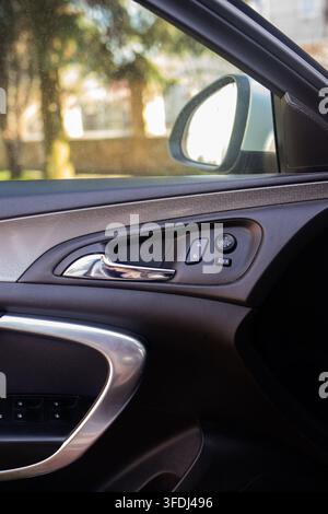 Open driver side door displays interior panel controls and chrome handle. Modern automotive details emphasize comfort functionality and safety. Stock Photo