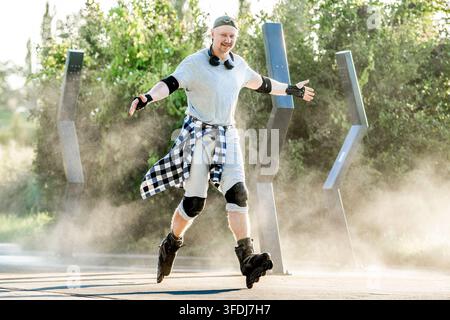 Man in protective gear balances on rollerblades while moving along a dusty park trail outdoors Stock Photo
