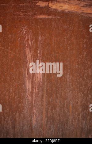 A close-up vertical photograph of a brown rusted metal sheet with prominent paint strokes and textured corrosion, creating a grunge industrial backgro Stock Photo