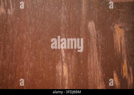 A close-up view of an old weathered rusty metal sheet featuring vertical scratches and mottled brown corrosion, perfect for an industrial grunge backg Stock Photo