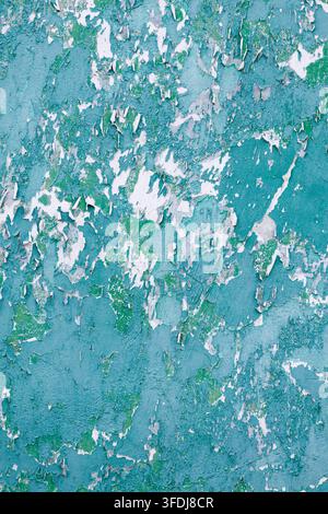 Close-up view of a weathered vertical wall surface covered in flaking turquoise paint, revealing a distressed white background suitable for grunge arc Stock Photo