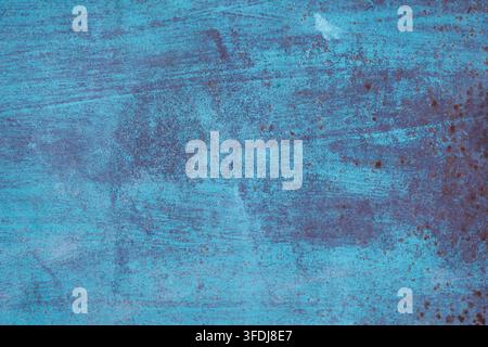 Close-up view of a weathered blue painted metal surface exhibiting rust spots and scratches, creating an industrial grunge background texture for desi Stock Photo