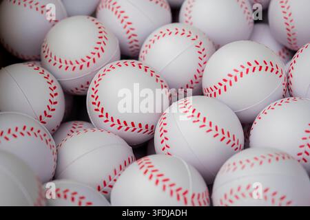 A close-up, full-frame view of numerous white foam baseballs with red stitched-look seams piled together, creating a repeating a circular pattern Stock Photo