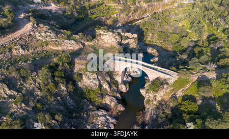 Ancient Rounded Stone Aerial view of an ancient stone bridge spanning a rocky stream in the ...
