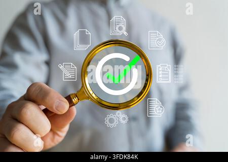 Magnifying glass highlights an approval check mark with document icons, illustrating quality assurance, audit, compliance, verification, certification Stock Photo
