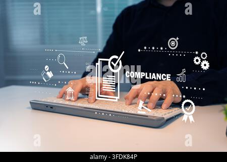Professional typing beside a digital compliance interface, illustrating regulation, audit, governance, risk control, certification, policy review, and Stock Photo