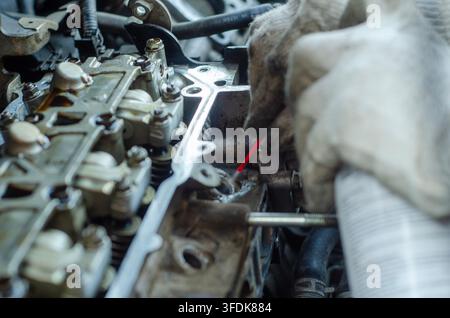 Mechanic wearing protective gloves works on a car engine focusing on internal components and mechanics for repair or maintenance Stock Photo