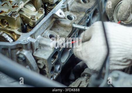 Mechanic wearing protective gloves works on a car engine focusing on internal components and mechanics for repair or maintenance Stock Photo