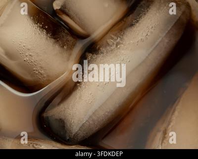 Macro closeup of ice cubes floating in a cold carbonated cola soft drink with fine condensation bubbles Stock Photo