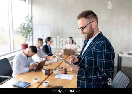 Smiling Businessman Using Digital Tablet Standing In Office Stock Photo