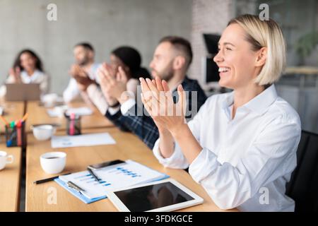 Happy Colleagues Applauding During Corporate Meeting Sitting In Modern Office Stock Photo