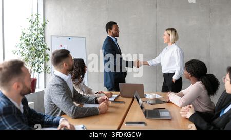 Businessman And Businesswoman Shaking Hands After Successful Deal In Office Stock Photo
