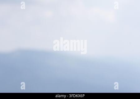 Soft abstract background of pale blue sky and distant mountains fading into dreamy haze. Gentle gradient and bokeh create a tranquil mood ideal for co Stock Photo
