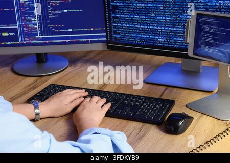 Software development and programming, developer writing code on computer with multiple monitors and tablet in office for web engineering project Stock Photo
