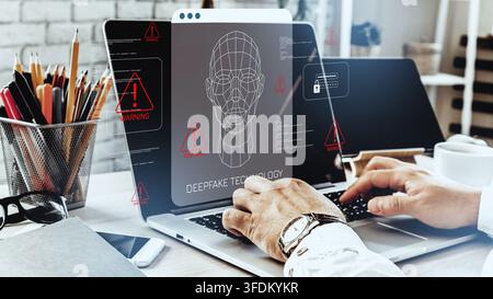 Deepfake technology and computer warning displayed on laptop while person works at desk in office Stock Photo