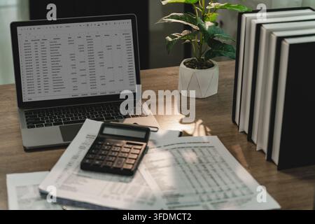 Laptop spreadsheet with calculator and financial reports on office desk for invoice review, receipt accounting, cash flow monitoring, bookkeeping, fin Stock Photo
