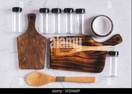 Kitchen set of wooden cutting boards, spatulas, bowls and spice bottles on the table top view Stock Photo