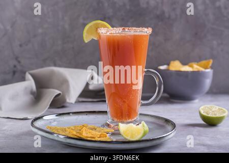 Michelada cocktail with tomato juice, beer and lime in a glass and nachos Stock Photo