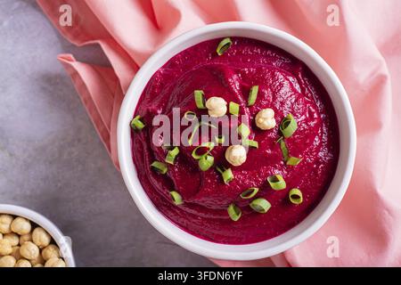 Close up of beetroot hummus in a bowl and chickpeas on the table top view Stock Photo