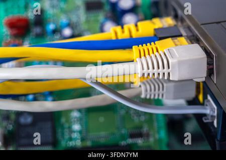 Cables are linked to a network switch showing connections in a computer hardware setup during daylight hours Stock Photo