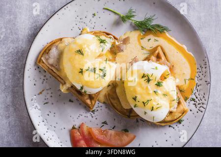 Closeup of eggs benedict and bacon on a crispy waffle for homemade breakfast. Top view Stock Photo
