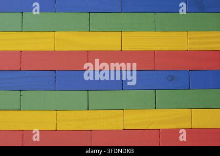 Close-up of a wall made from brightly colored wooden toy blocks (red, yellow, green, and blue) arranged in a neat geometric pattern and texture, suita Stock Photo