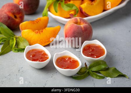 Delicious Homemade Peach Jam in Small White Bowls with Fresh Sliced Peaches Stock Photo