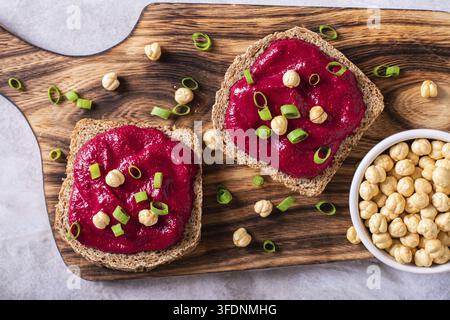 Close up of rye bread sandwiches with beetroot hummus and herbs on a cutting board top view Stock Photo