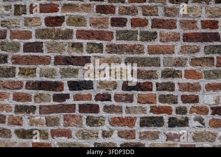 Close view of multicolored aged bricks and pale mortar creating an irregular weathered masonry texture in the historic old town centre of Bruges Brugg Stock Photo
