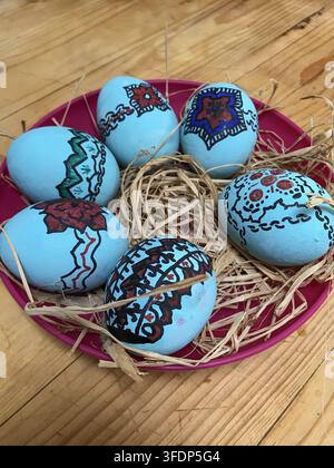 Hand painted light blue Easter eggs decorated with traditional ornaments placed in a nest on a wooden table Stock Photo