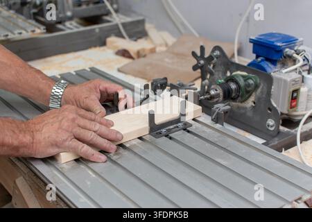 Worker hands adjusting wooden plank on aluminum machine table Stock Photo