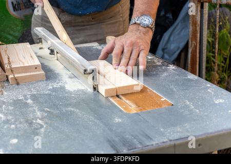 Carpenter using push stick on table saw blade close up Stock Photo