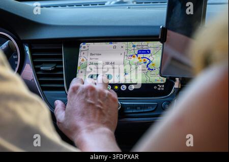 Iserlohn, Germany - August 13, 2026: Person's hand touching car infotainment screen displaying navigation map with routes. Stock Photo